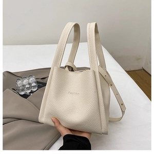 Detailed macro view of cream-colored lychee leather bucket bag with Fashion embossing