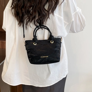 Modern black pleated bucket bag with gold lettering and adjustable crossbody strap