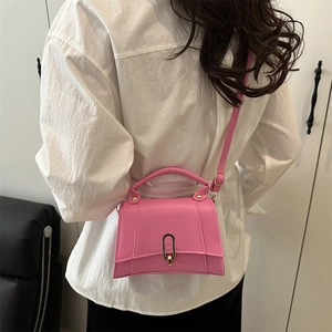 Sac bandoulière rose en forme de sablier avec base incurvée et boucle dorée en U