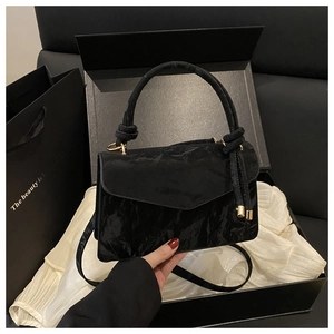 Dettaglio della borsa nera in pelle verniciata con hardware dorato e confezione