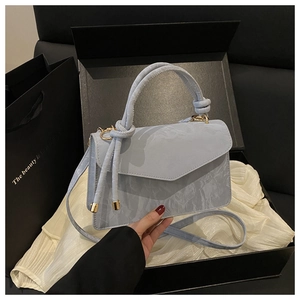 Dettaglio borsa in pelle testurizzata azzurro chiaro con finiture dorate e manico annodato