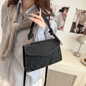 Borsa a mano alla moda in pelle nera plissettata con tracolla in un interno moderno
