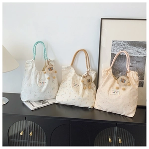 Three floral canvas tote bags with rope handles and plush lion charms in a home setting