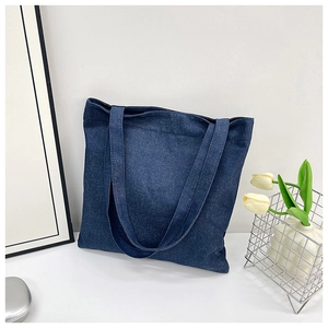 Detail of blue denim tote bag with white tulips and metal basket in a lifestyle setting