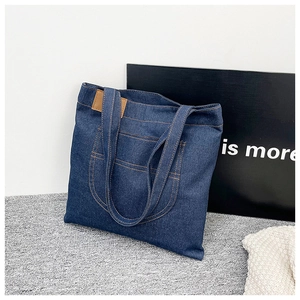 Deep blue denim tote bag detail featuring contrast orange stitching and front pocket
