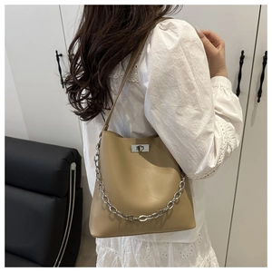 Détail du sac seau en cuir kaki avec chaîne en métal argenté et fermoir rotatif sur modèle