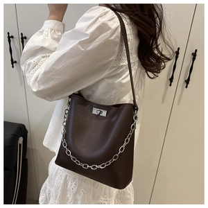Détail du sac seau en cuir café avec chaîne métallique argentée et fermoir pivotant