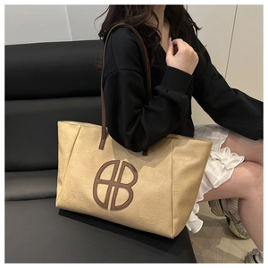 Detail view of khaki tote bag with BB logo and wrinkled leather texture on a model