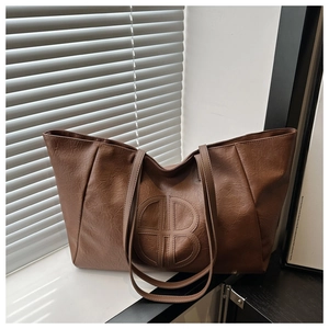 Close-up of vintage brown tote bag with embossed circular logo and textured faux leather