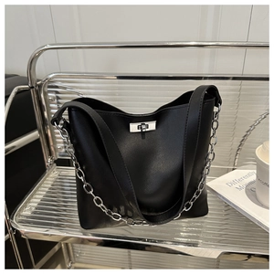 Détail du sac seau en cuir noir avec un fermoir rotatif argenté et une bandoulière chaîne