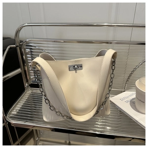 Détail du sac seau crème avec fermoir rotatif argenté et bandoulière en chaîne