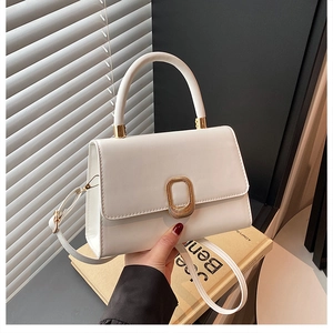Detail of white leather trapezoid handbag with gold metal clasp and detachable strap