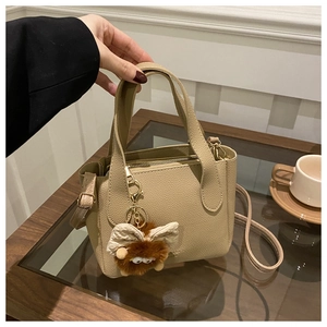 Detail of khaki lychee grain tote bag featuring dual handles and brown plush charm accessory