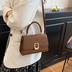 Minimalist vintage dark brown handbag with gold oval clasp for women in a classic office setting