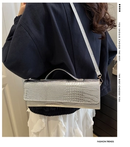 Details der silbernen Handtasche mit Krokodilprägung und Schultergurt am Modell