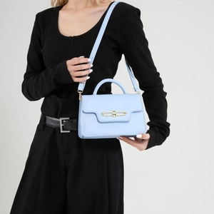 Minimalist light blue PU leather handbag with gold lock shown on model with black outfit