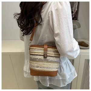 Detail showing contrast stitching on the woven straw bucket bag with premium leather strap