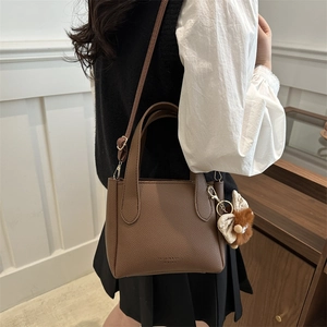 Brown litchi texture bucket tote bag with plush charm and adjustable shoulder strap