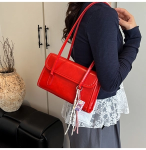 Détail d'un sac à bandoulière rouge avec fines bretelles et finition en cuir brillant