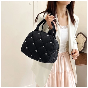 Détail du sac fourre-tout matelassé noir avec motifs nœuds blancs et texture rembourrée