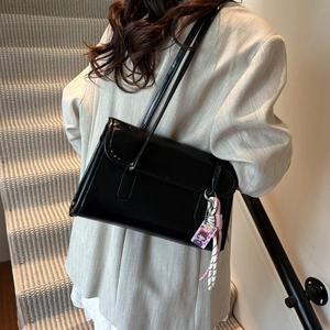Sac sous le bras en cuir noir minimaliste avec bandoulière et petit charme coloré