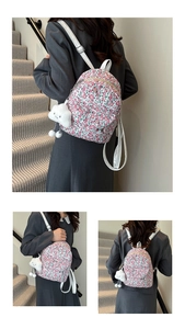 Close-up of floral school backpack with white cloud plush charm and leather straps