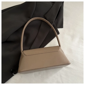 Sac baguette minimaliste en cuir kaki foncé posé à plat avec un blazer noir chic