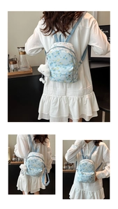 Detail view of light blue floral backpack featuring small yellow flowers and plush bear charm
