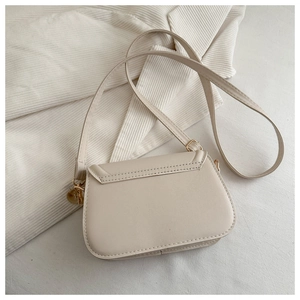Close-up of cream PU leather saddle bag with gold-tone metal buckles and strap details