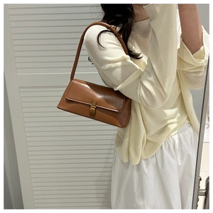 Gros plan d'un sac bandoulière en cuir marron avec fermoir en métal vintage et fini lisse