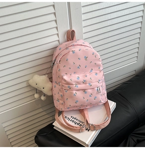 Close-up of pink floral backpack with metal zippers and cute cloud plush keychain