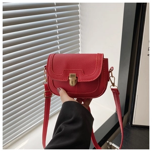 Close-up of red lychee pattern leather crossbody bag featuring vintage gold metal clasp