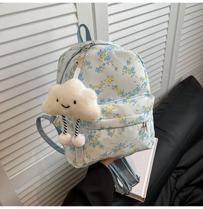Detail of light blue floral backpack with plush cloud pendant and zipper pocket