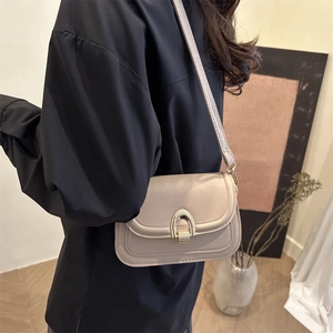 Minimalist beige saddle bag for women with elegant gold horseshoe buckle and slim strap