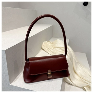 Detail of burgundy leather shoulder bag with vintage gold buckle on white stairs