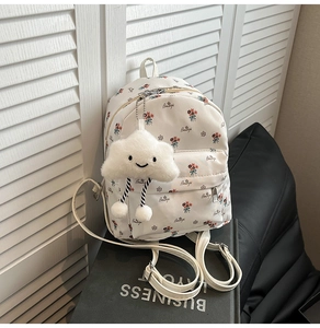 Close-up of white floral mini backpack with a plush cloud charm and adjustable straps