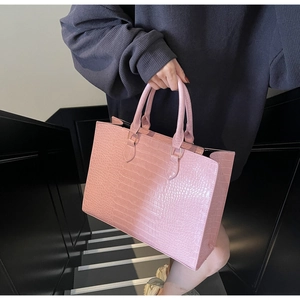 Pink faux crocodile leather tote bag shown in a professional fashion lifestyle photoshoot