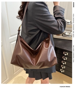 Side view of a vintage brown leather shoulder bag with a wide strap and gold buckle