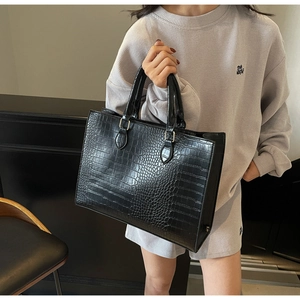 Detail showing high-quality crocodile texture on black PU leather tote bag with round handles