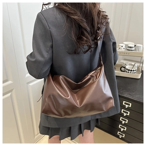 Detail view showing the soft texture and natural pleats of the brown PU leather tote bag