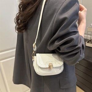Minimalist white litchi leather crossbody bag with gold buckle on a grey suit model