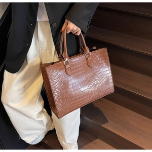 Chic brown crocodile pattern tote bag shown by model on a wooden staircase