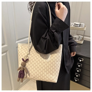 Detail of large canvas tote bag with M-pattern and purple rabbit pendant on shoulder
