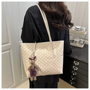 Detail of monogram tote bag featuring ivory M pattern and a plush rabbit charm