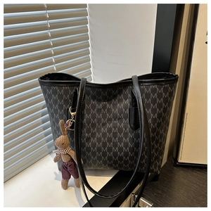 Detailed view of the dark tote bag with M-letter prints and a cute rabbit charm accessory