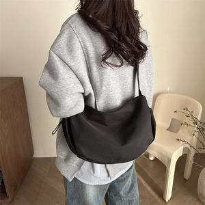 Large black nylon crescent crossbody bag for men and women shown in lifestyle setting
