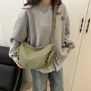 Green nylon dumpling crossbody bag with adjustable strap and casual drawstring detail