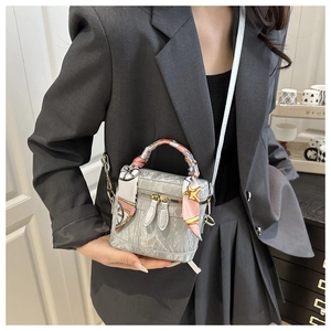 Detail of grey marble textured crossbody box bag with silk scarf on the handle
