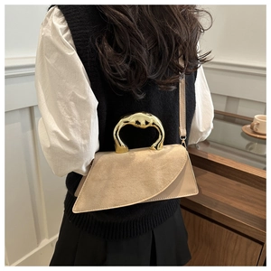 Chic beige crossbody bag featuring sculptural gold handle and mixed texture suede detail