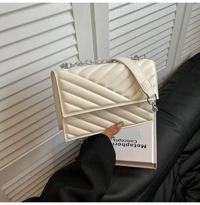 Gros plan sur le sac à bandoulière matelassé blanc crème avec chaîne argentée et cuir